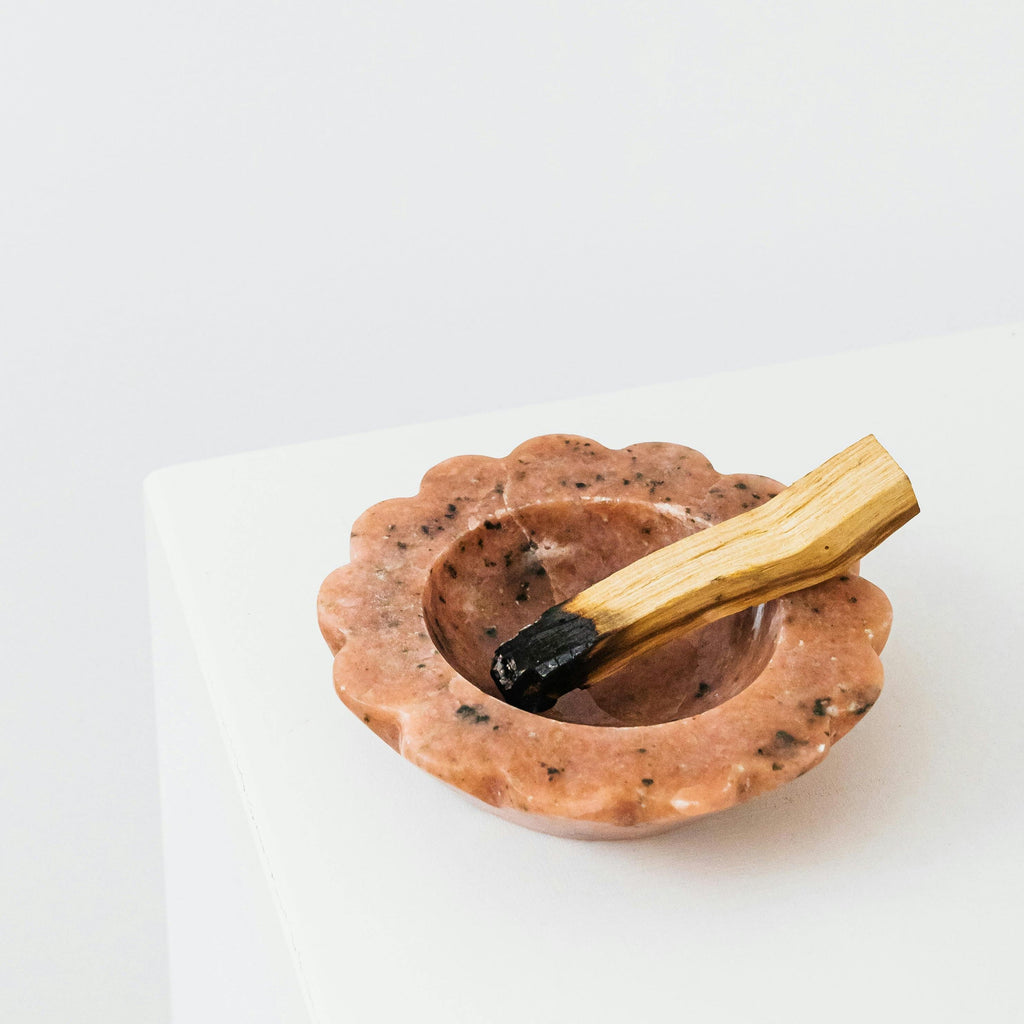 Lighting a single Palo Santo stick to release calming wood scent for a deep sleep sanctuary