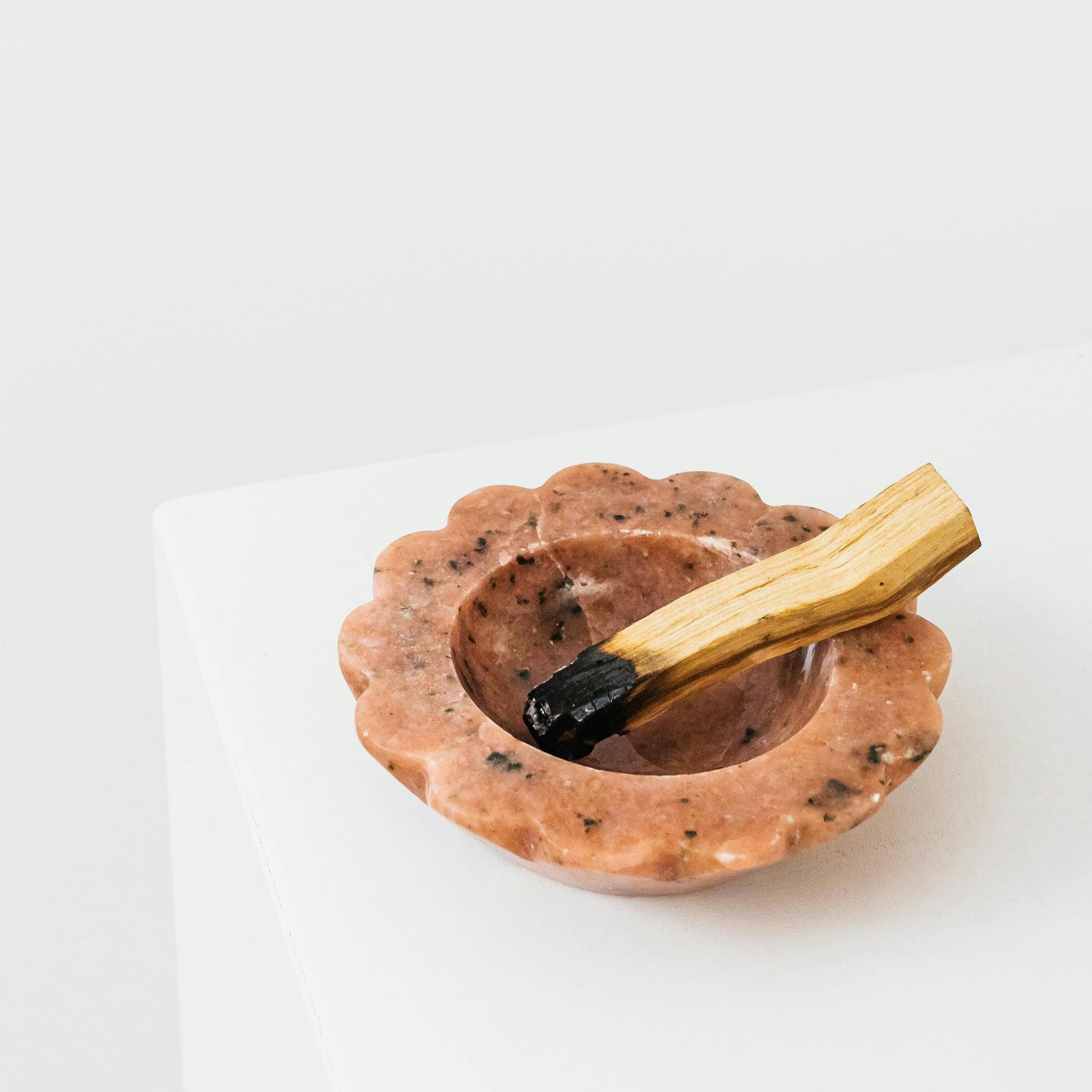 Lighting a single Palo Santo stick to release calming wood scent for a deep sleep sanctuary